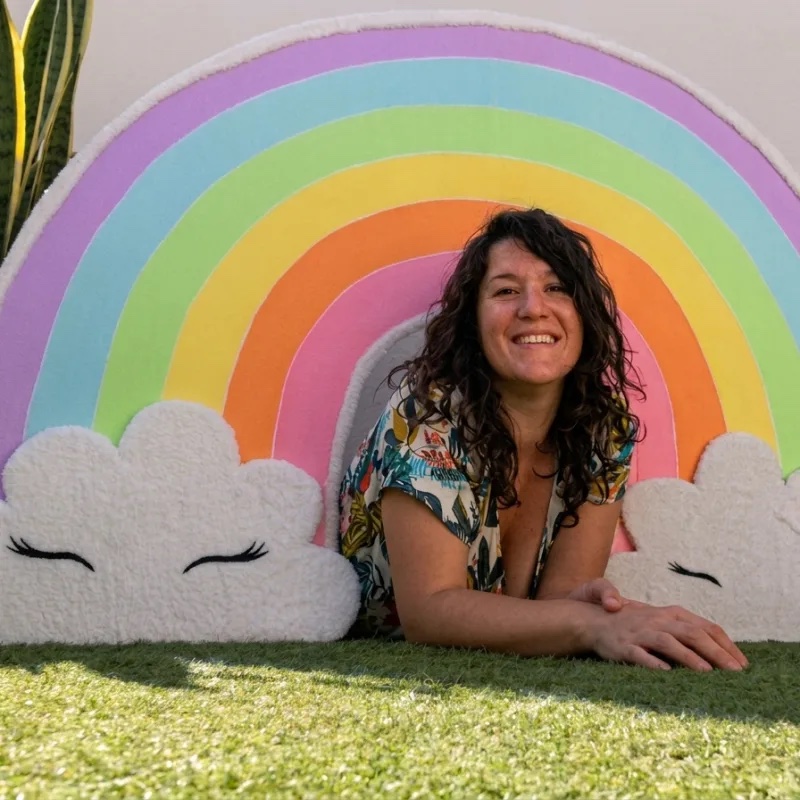 Grand décor arc-en-ciel pastel réalisé par Totem pour un événement, avec Claire Lys allongée devant